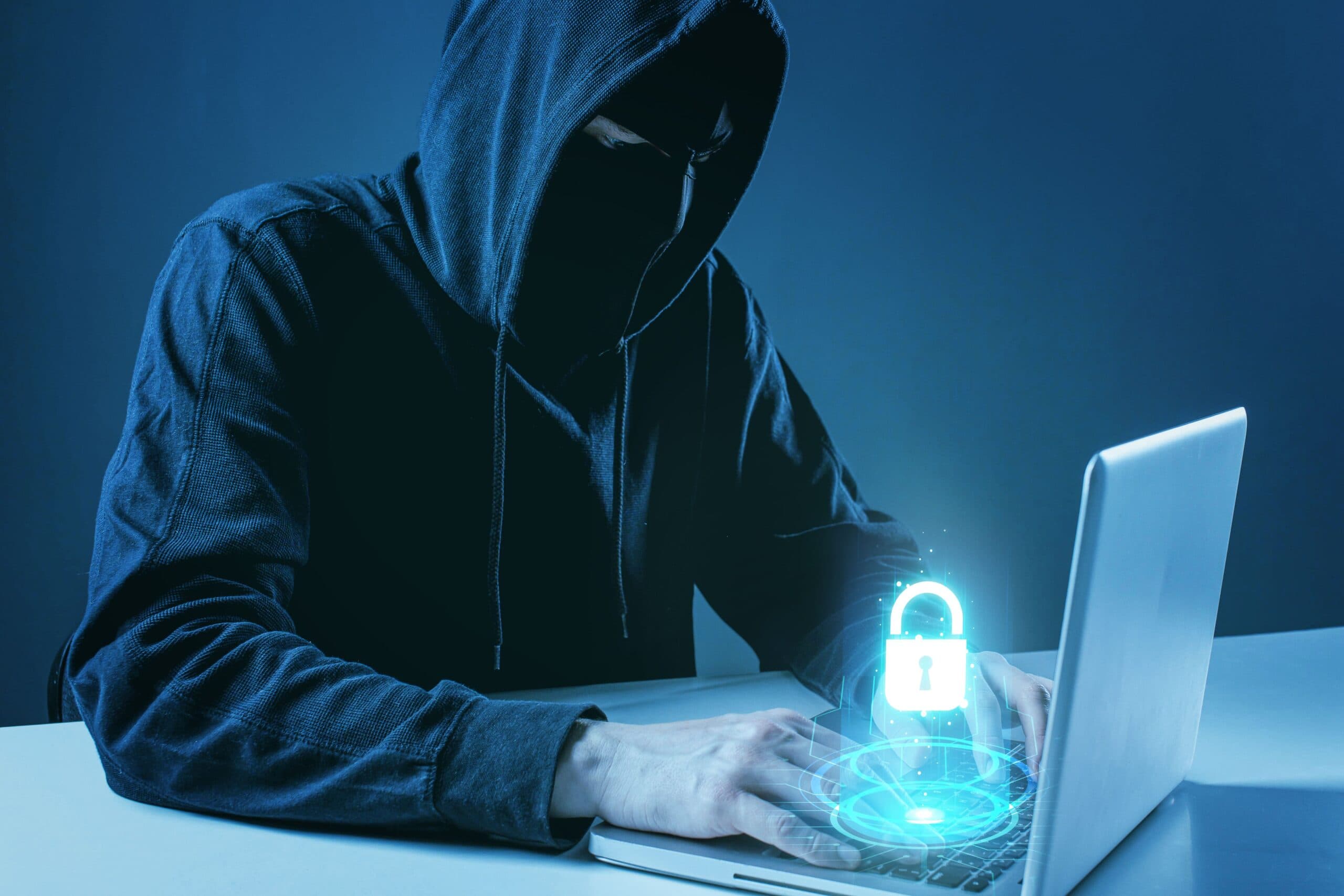 homem encapuzado mexendo no computador (tipos de golpe)