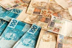 Consórcio de bens duráveis: diversas notas de cinquenta e cem reais estão espalhadas.