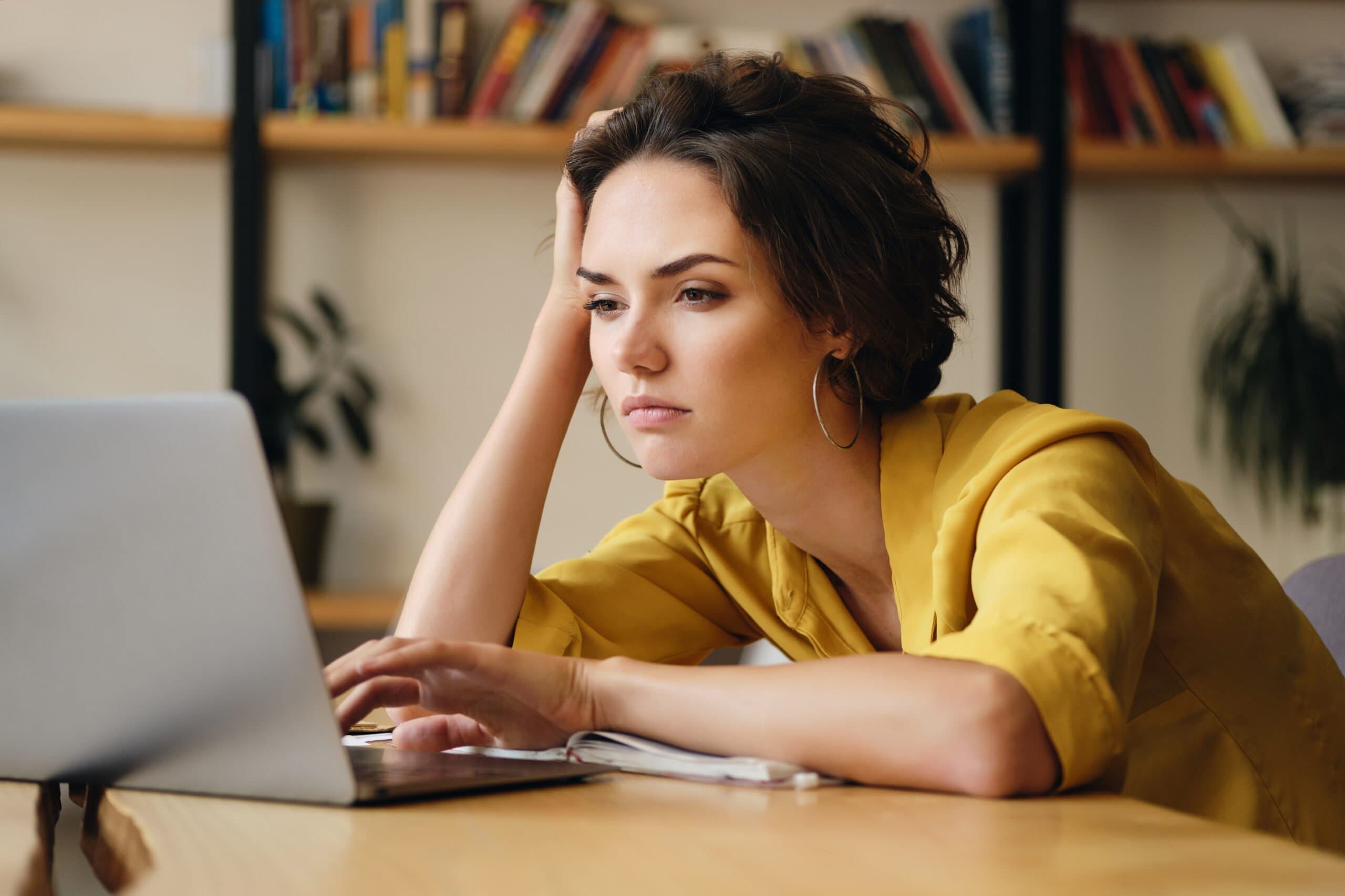 Empréstimo pessoal: uma mulher está sentada à mesa com um notebook e parece estar chateada.