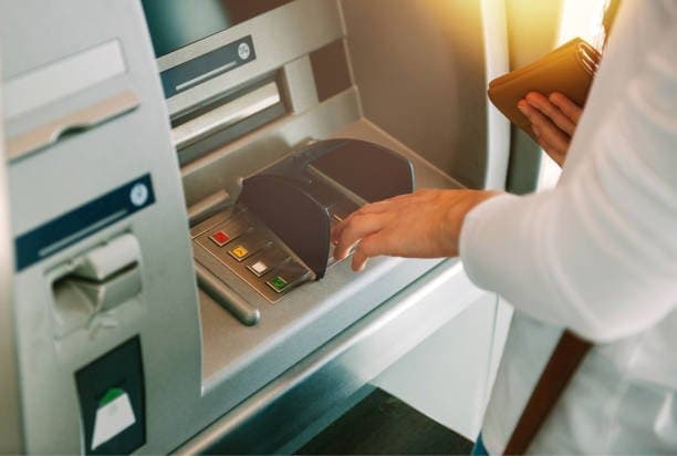 Fim do DOC e TED: uma pessoa utilizando o caixa eletrônico de um banco.