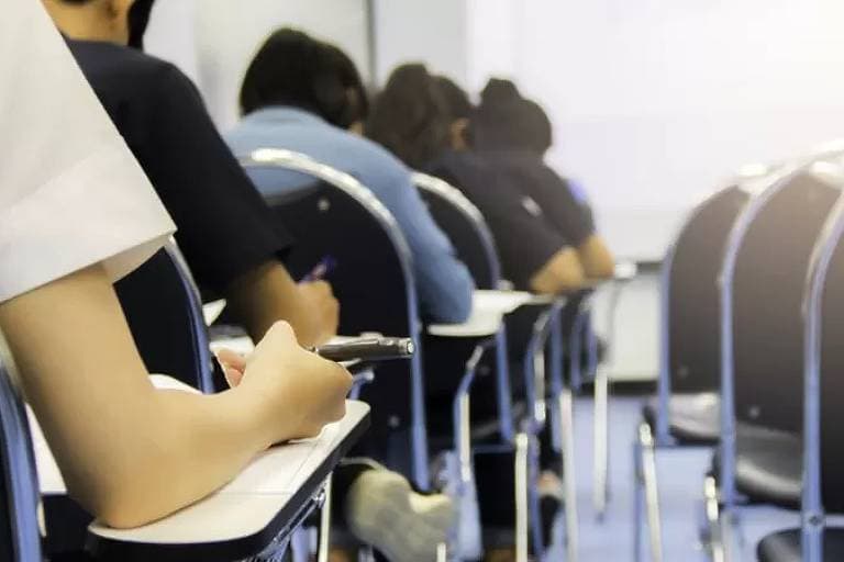 Quem tem nome sujo pode prestar concurso: diversas pessoas estão sentadas, enfileiradas, realizando provas.