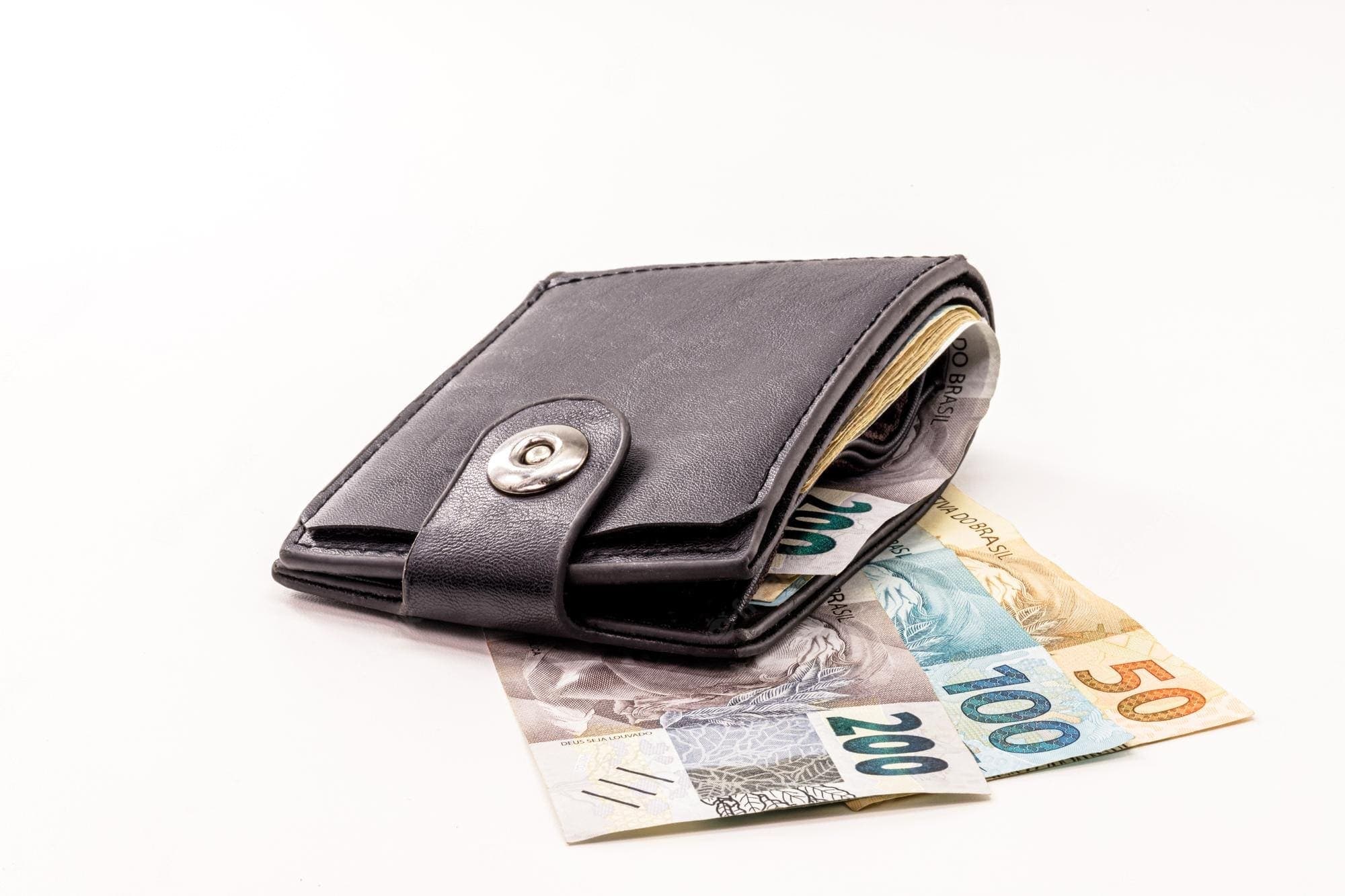 Empréstimo para aposentado: uma carteira está em cima de uma nota de cinquenta, uma de cem e outra de duzentos reais.