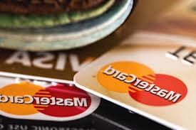 Estorno no cartão de crédito: dois cartões de bandeira Mastercard e um de bandeira Visa estão postos um sobre o outro.