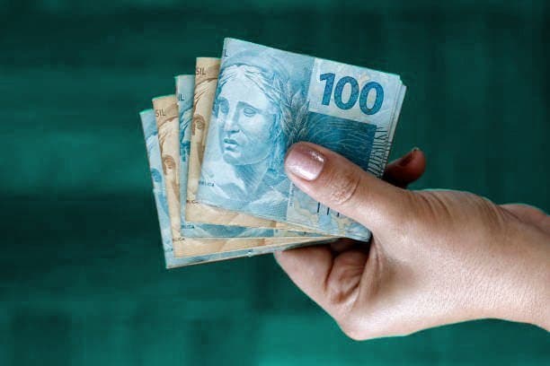 empréstimo: mão segurando notas de cem e cinquenta reais