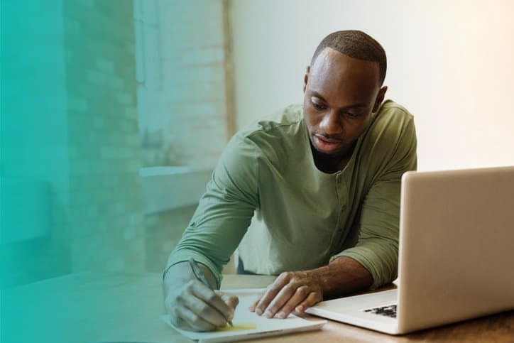 empréstimo pessoal: homem em frente ao computador realizando anotações