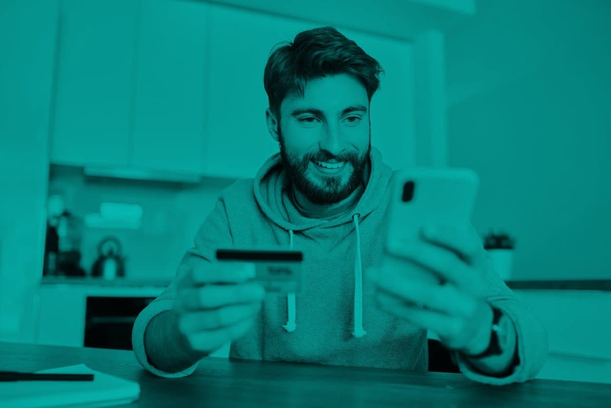 cartão de crédito: homem sorrindo segurando um cartão e um celular