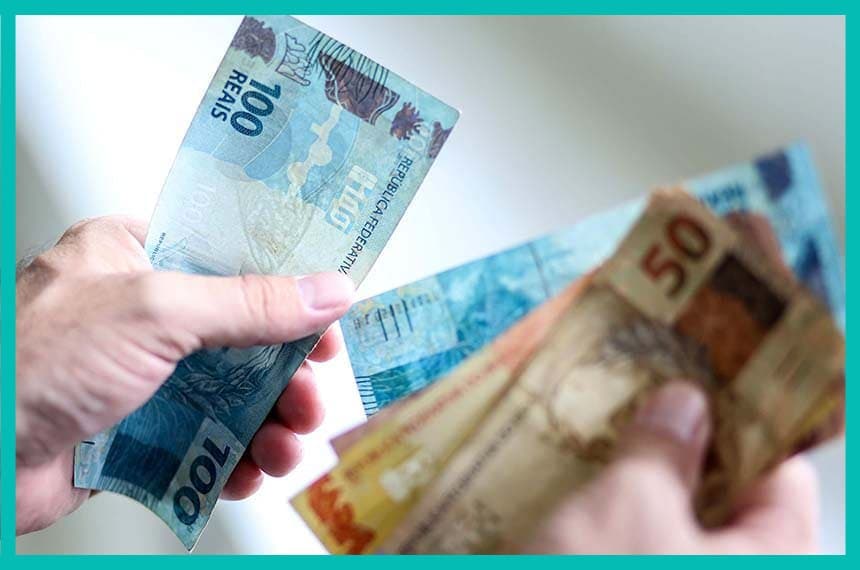 empréstimo: mãos segurando notas de cinquenta e cem reais