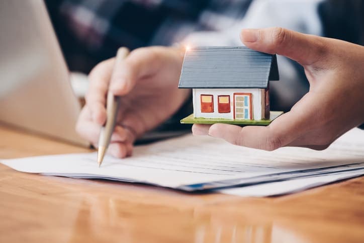 financiamento de imóvel: maquete de casa e papéis ao fundo