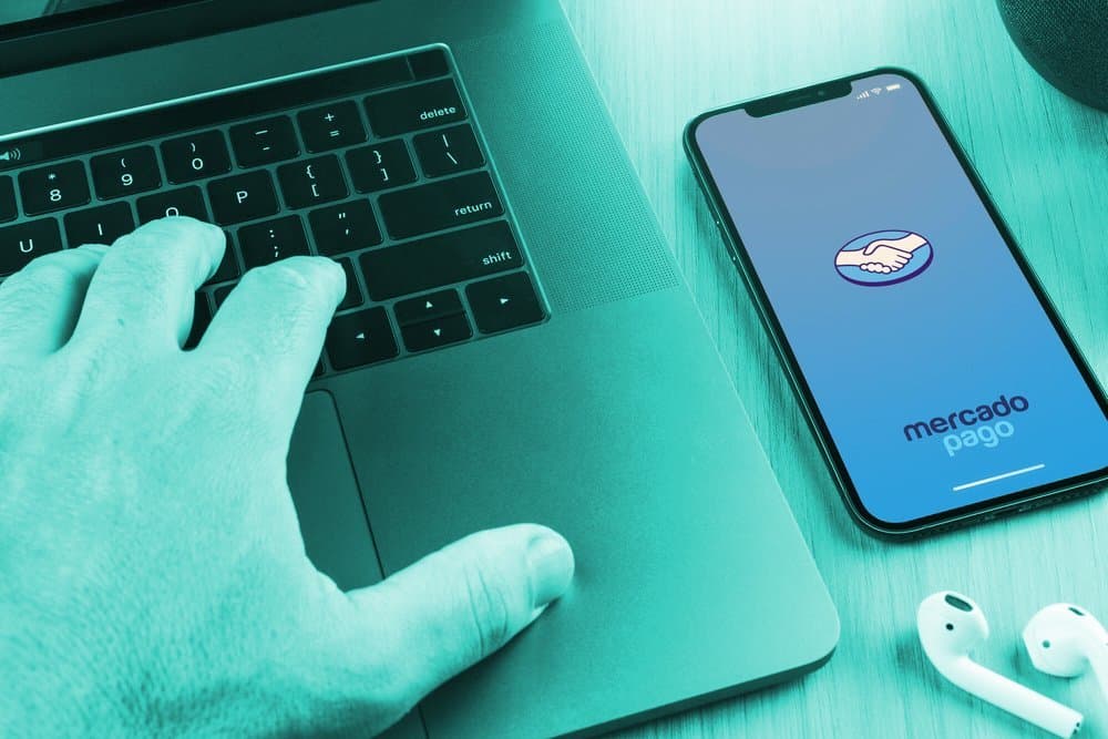 cartão de crédito: computador e celular ao lado mostrando na tela o logo do mercado pago