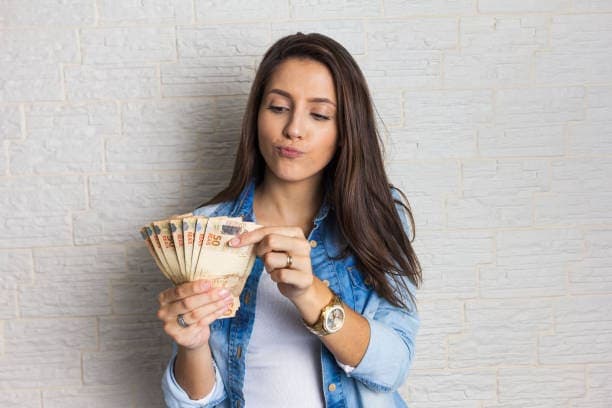 Saque-aniversário: mulher contando notas de cinquenta reais