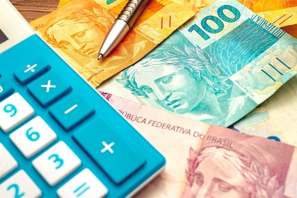 décimo terceiro: notas de dinheiro, caneta e calculadora.