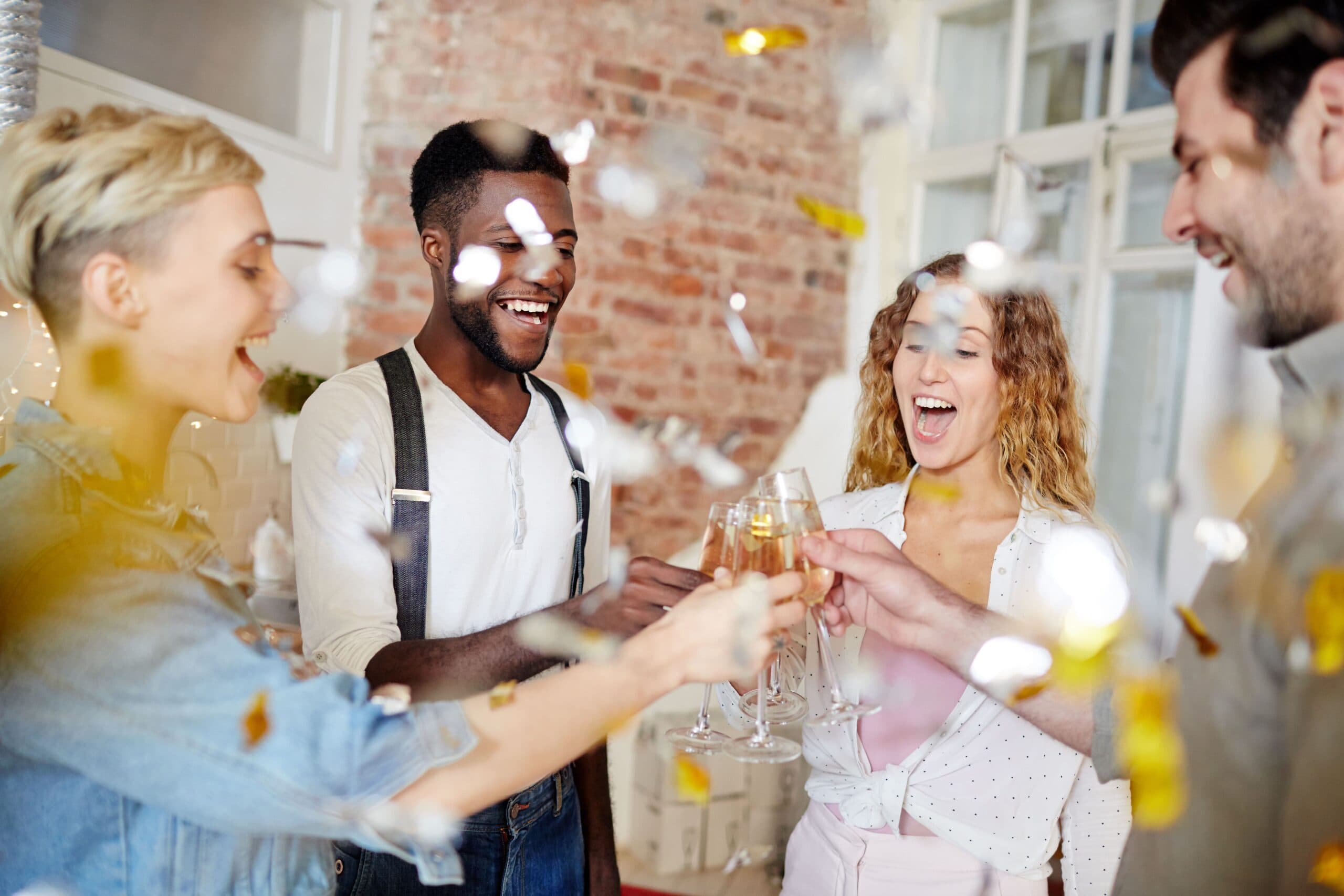 Empréstimo para fazer festa: quatro pessoas estão brindando e há confetes caindo sobre elas.