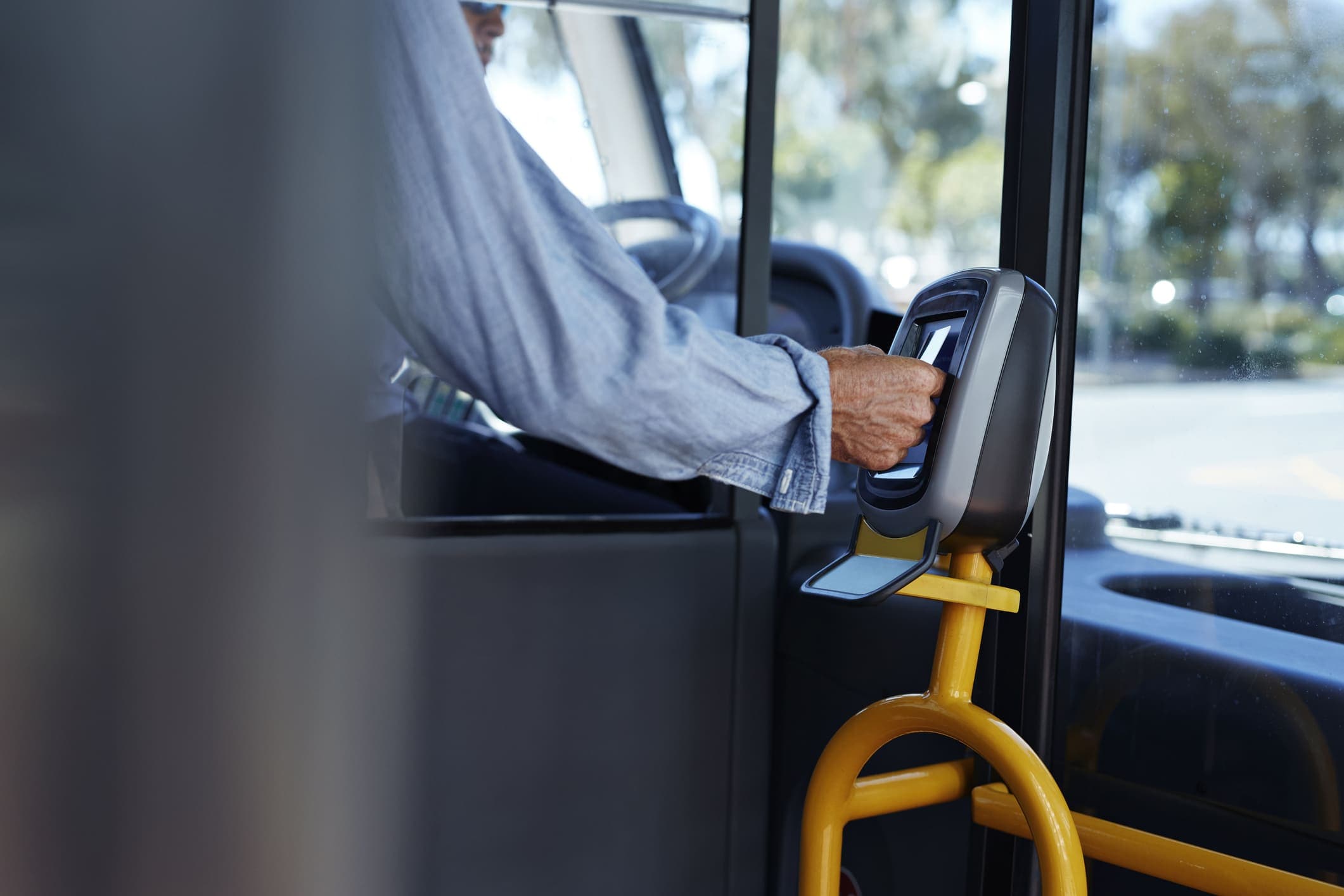 Vale-transporte: uma pessoa está dentro do ônibus, aproximando o cartão de um leitor, para pagar a passagem.