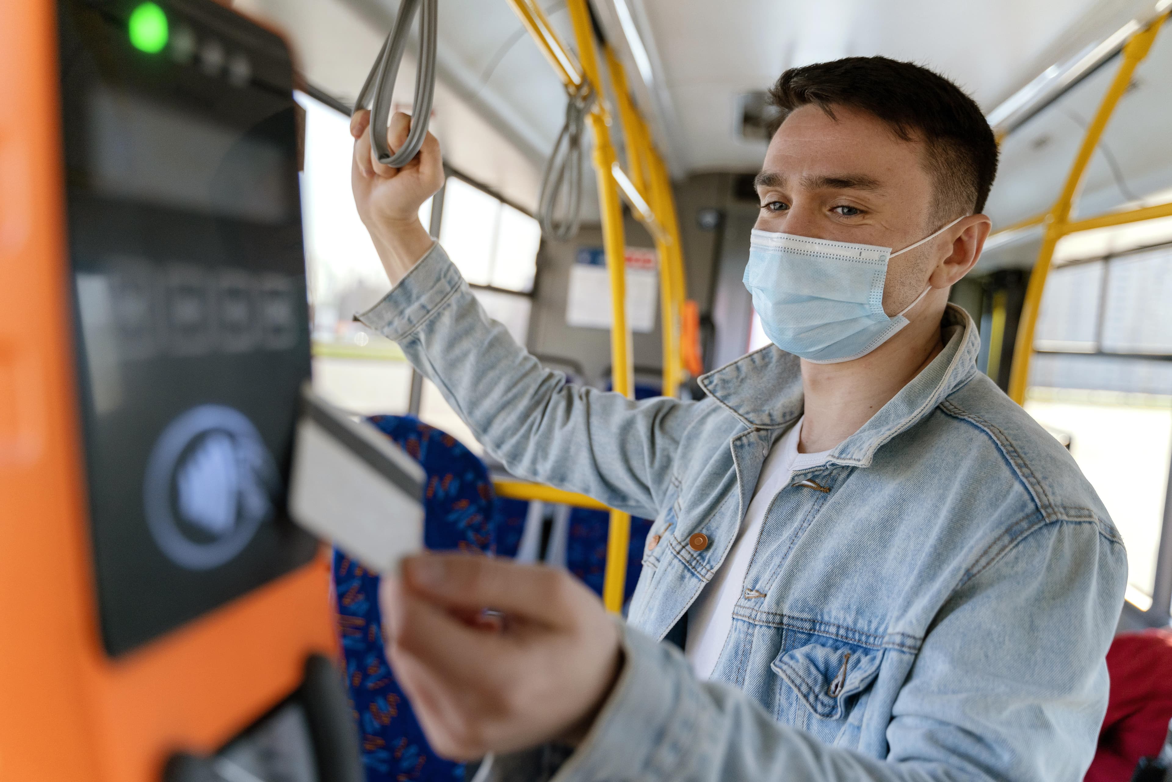 Vale-transporte: um homem branco aproxima um cartão magnético do leitor dentro do ônibus, para a pagar a passagem do transporte.