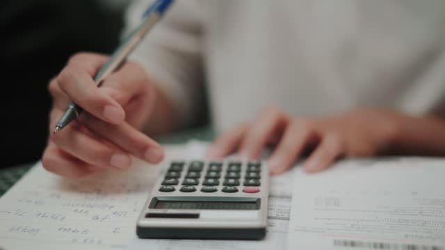 Salário liquido: um homem está segurando uma caneta e utilizando uma calculadora com a mesma mão.