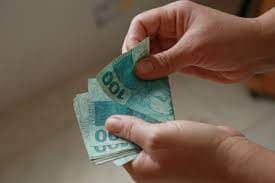 Antecipação da restituição do IR: um homem conta notas de cem reais.