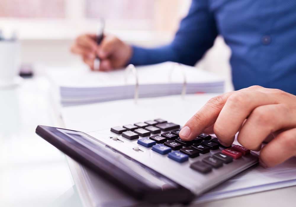 Financiamento: um homem utiliza a calculadora enquanto realiza anotações em um caderno.