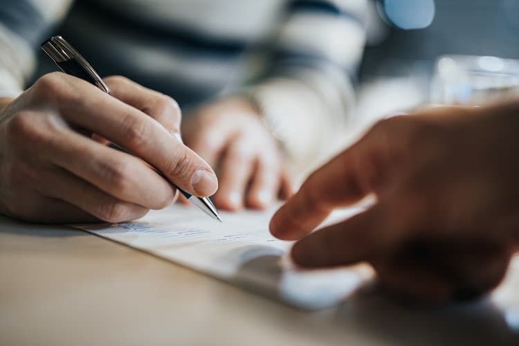 Grupo de consórcio: uma pessoa assina um documento, enquanto outra aponta para o item
