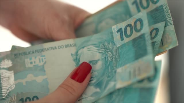 Dinheiro rápido sem burocracia: uma mulher está contando notas de cem reais.