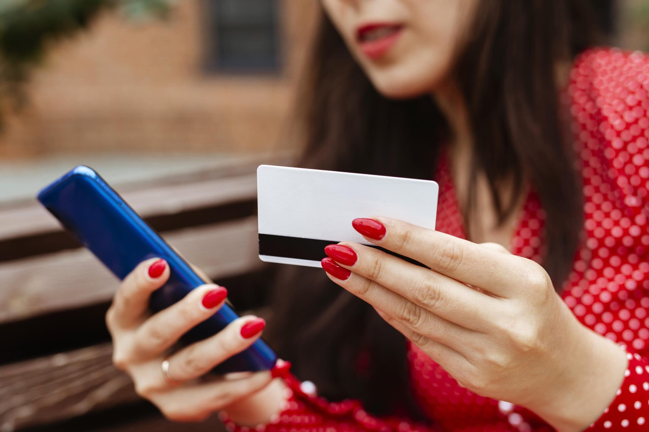 mulher segurando cartão de crédito e um aparelho celular.