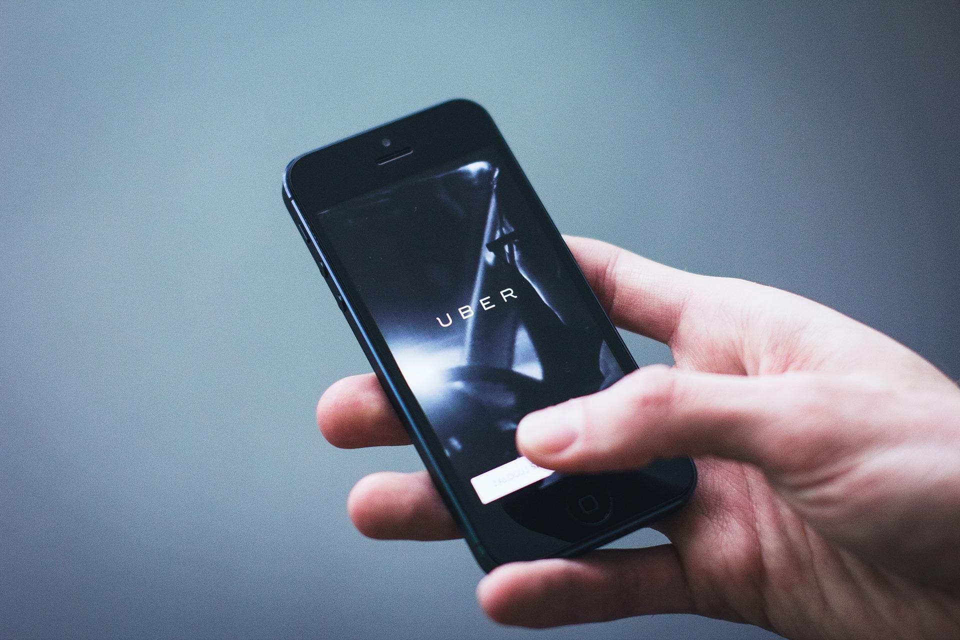 homem segurando celular com app da Uber (cartão Flash)