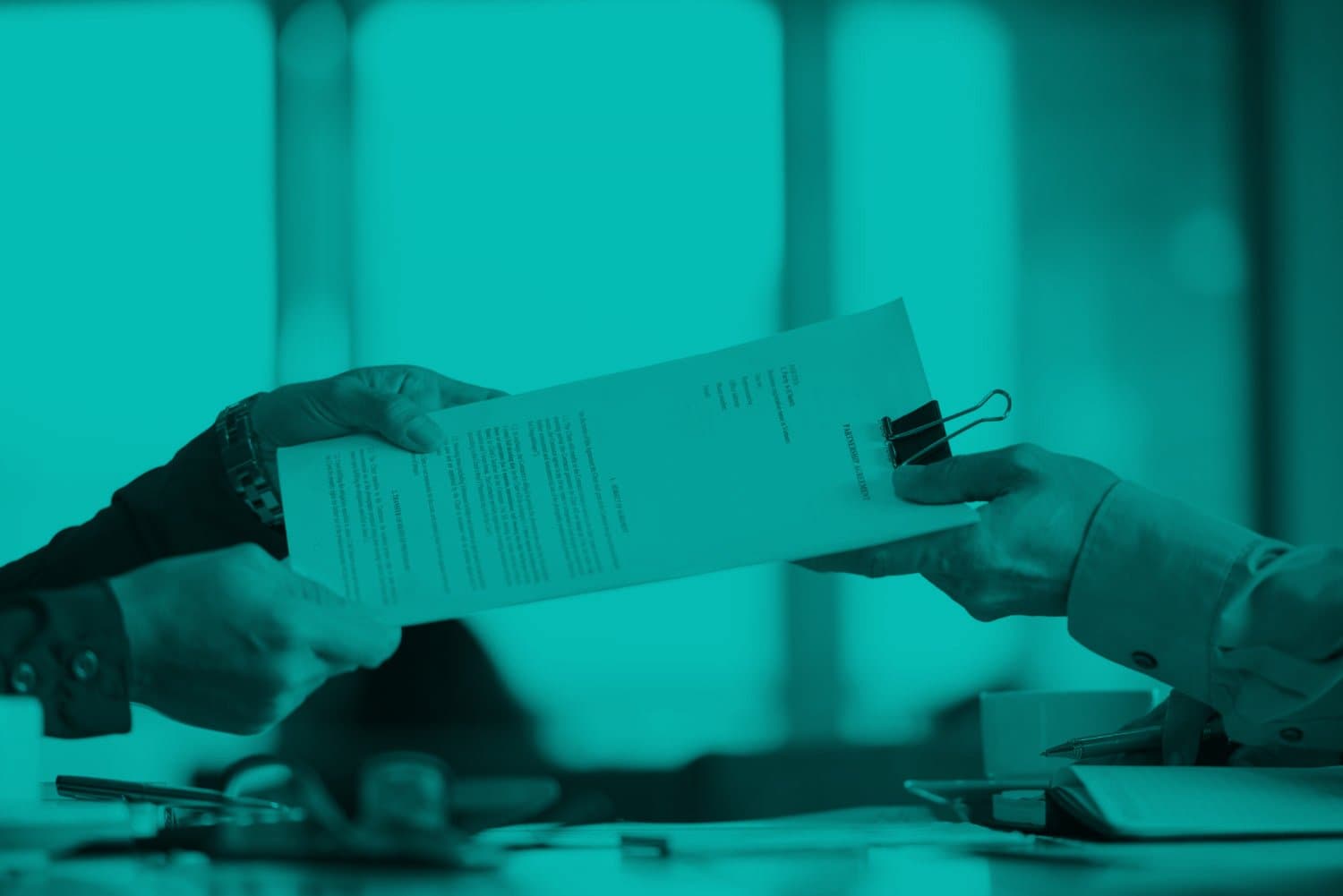 Empréstimo consignado: uma pessoa entrega um papel com texto digitado à outra pessoa. Na mesa há uma agenda aberta.