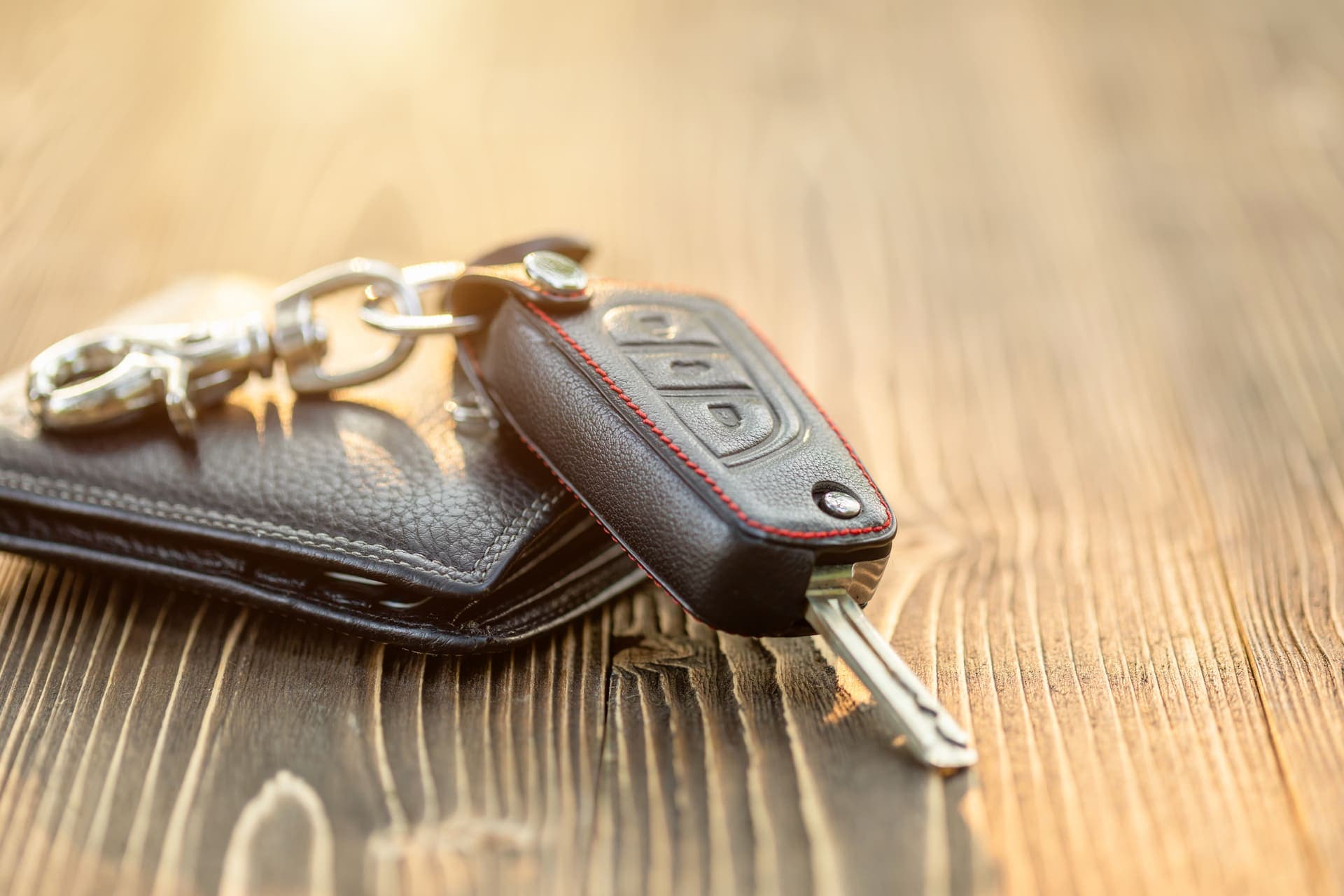 Financiamento de veículo: uma carteira de cor escura está em cima de uma superfície e há uma chave de carro apoiada.