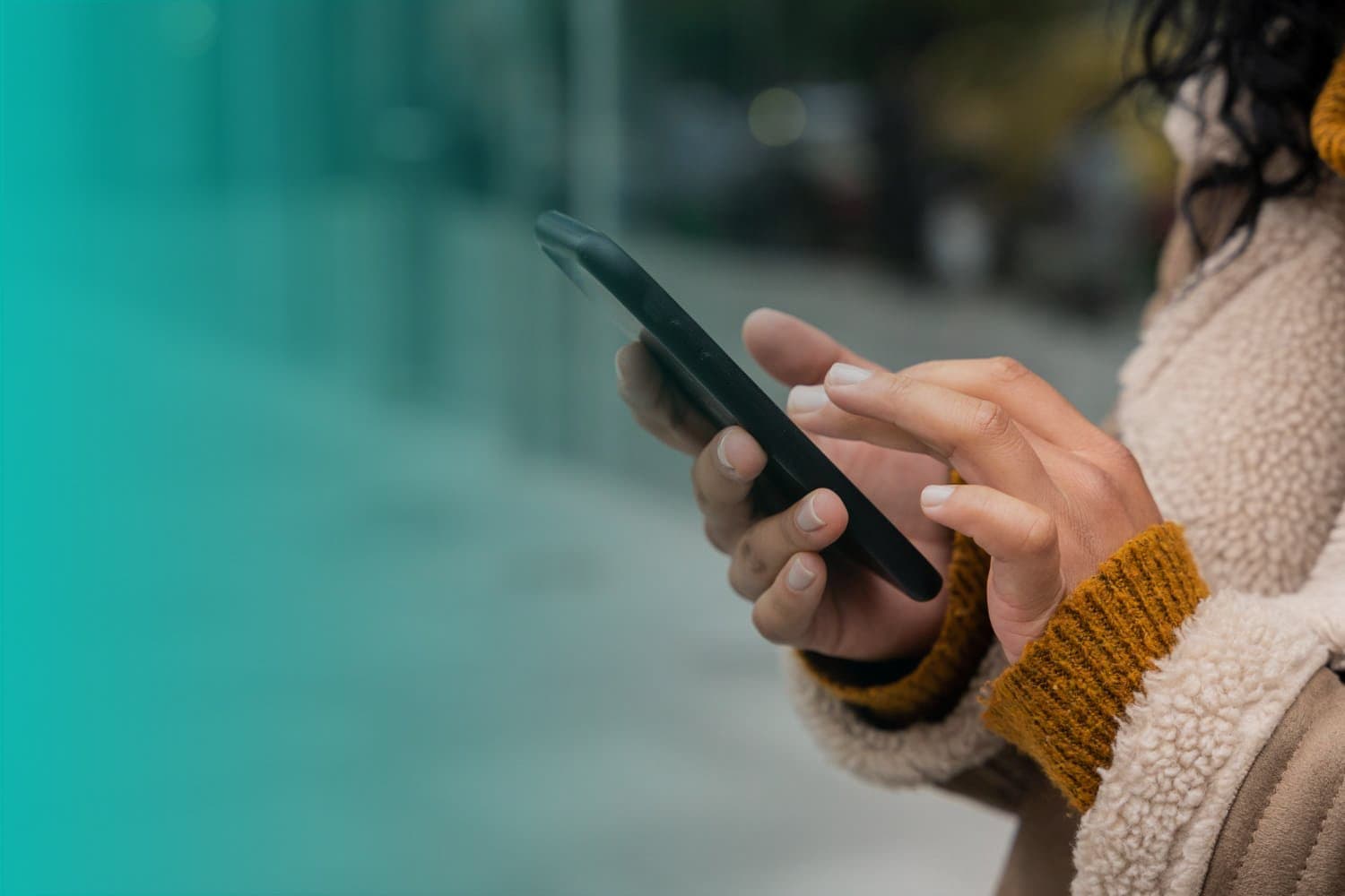 Cartão Cidadão: uma mulher está na rua, de casaco bege e mexendo no celular.