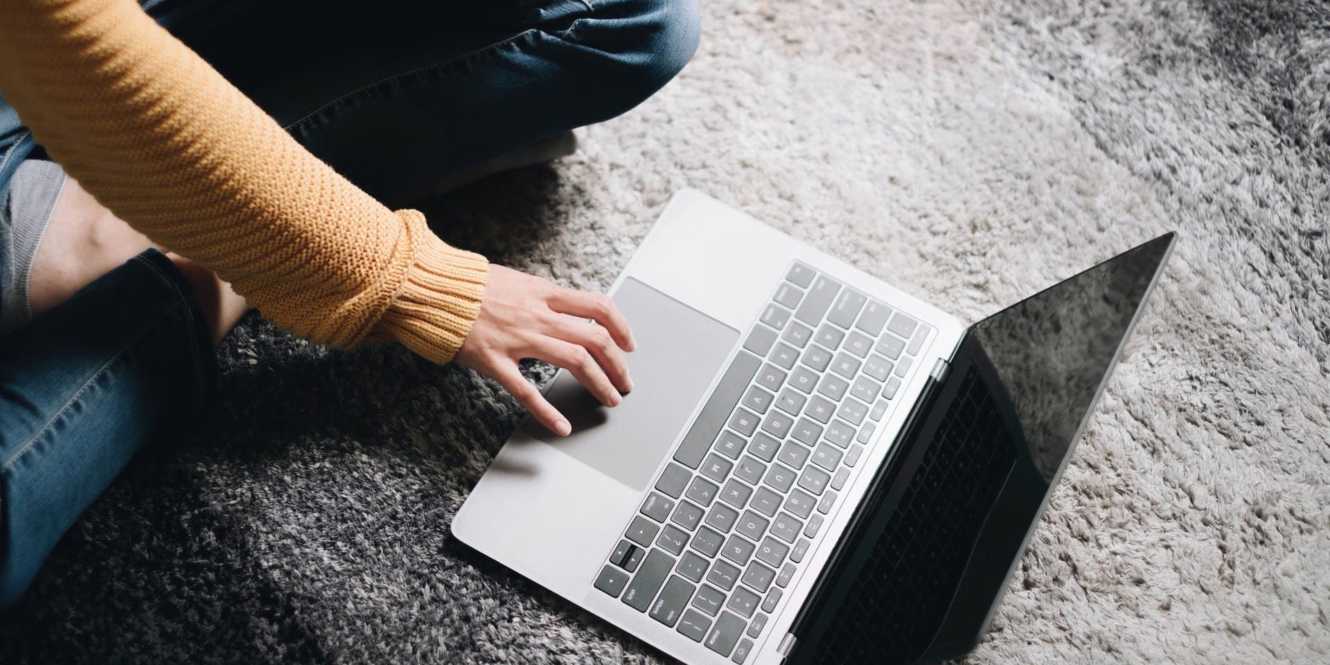 Senha: uma mulher está sentada no chão e mexendo no notebook.