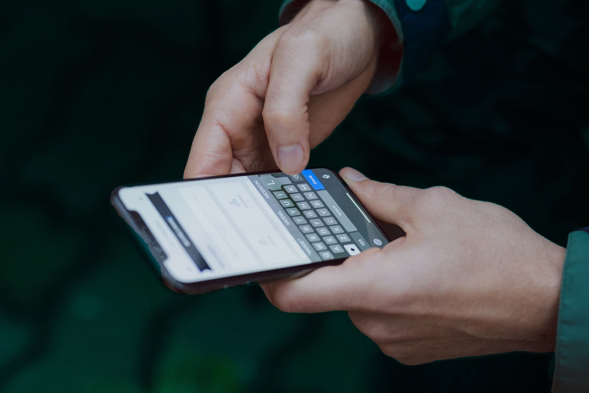 Caixa Tem: uma pessoa mexe em no celular, enquanto o segura com as duas mãos.