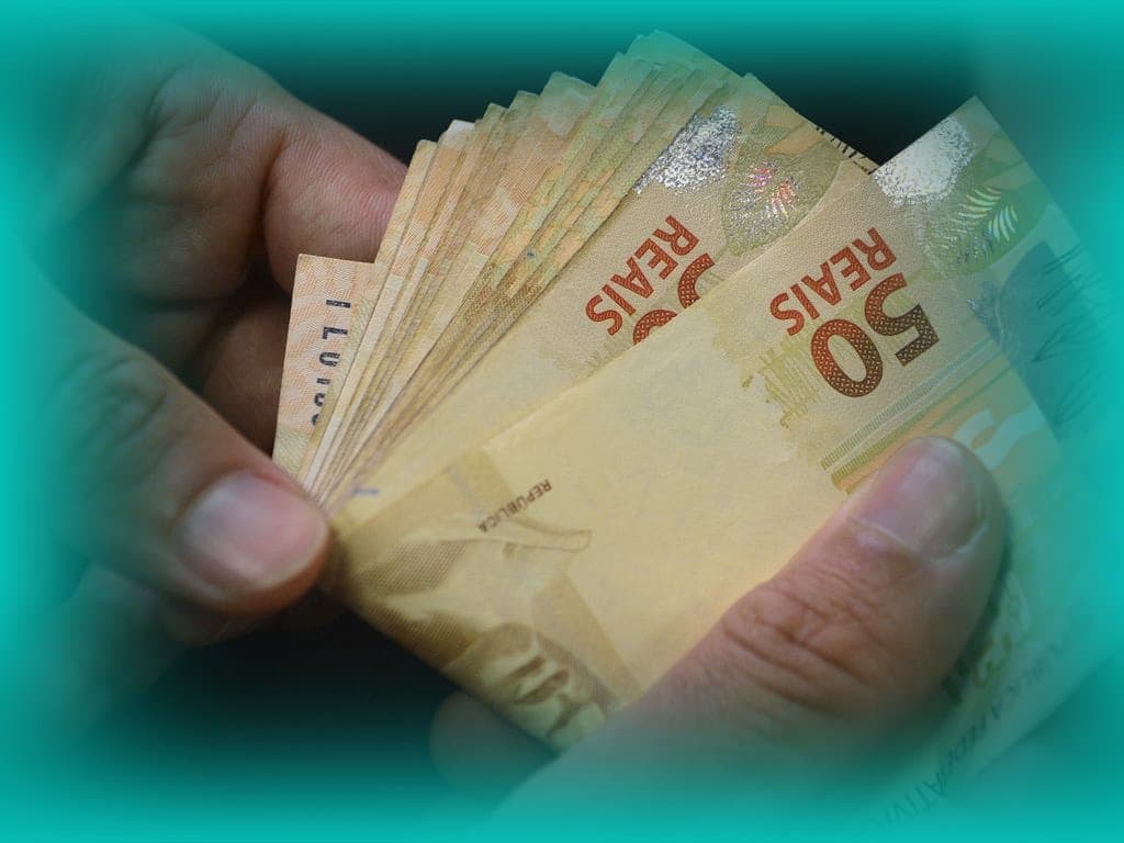 PIS: uma pessoa conta algumas notas de cinquenta reais.