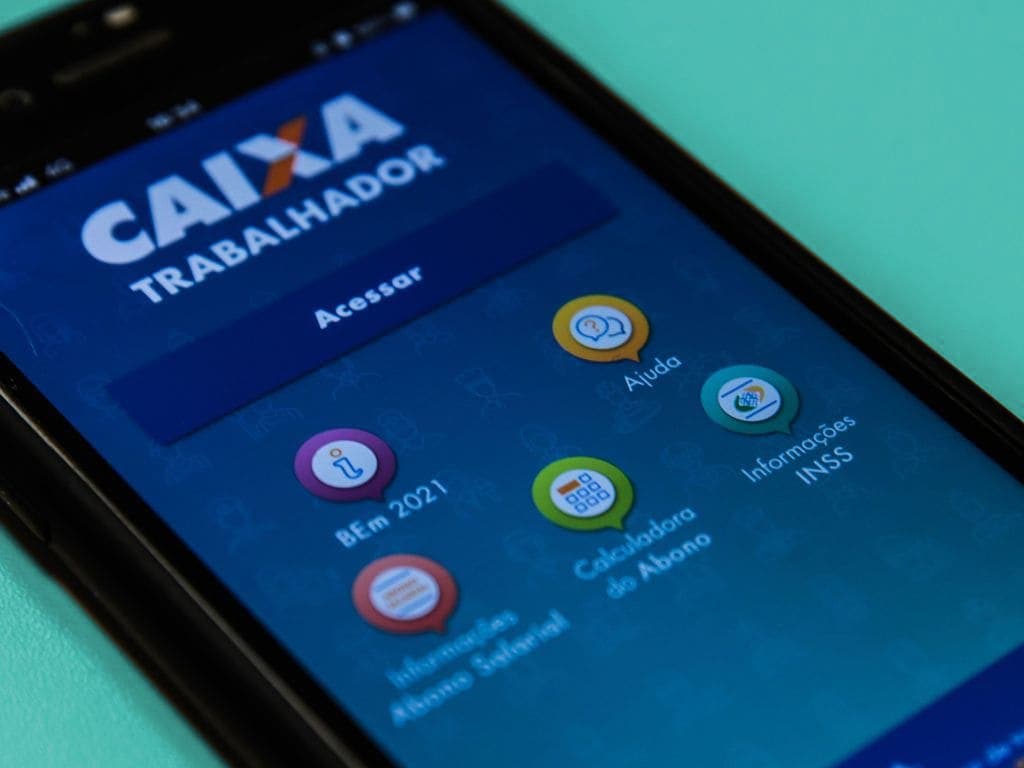 Tela do celular mostra o aplicativo Caixa Trabalhador, com fundo azul e ícones coloridos.