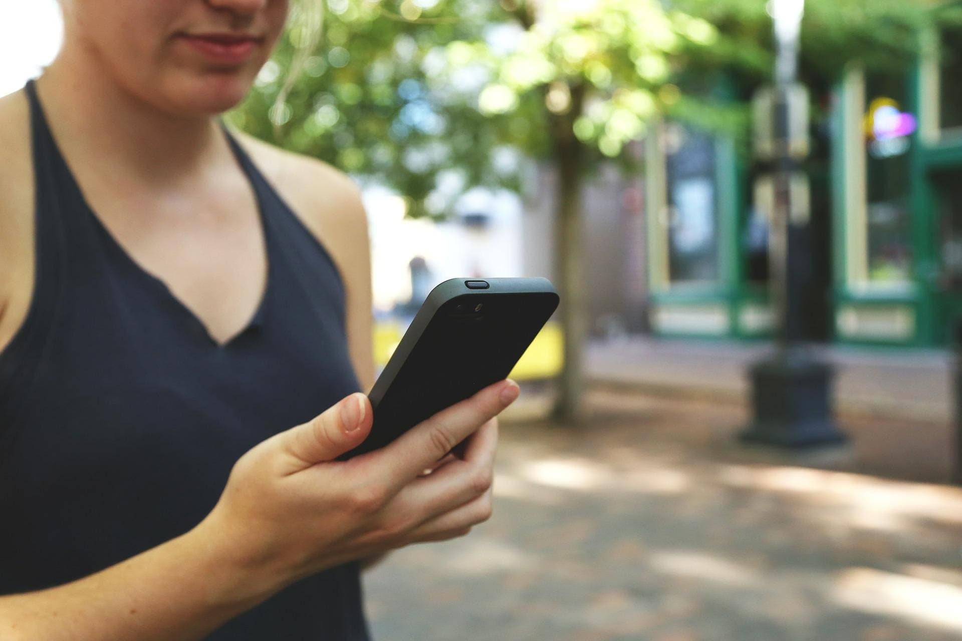 mulher usando celular (conta corrente para poupança Itaú)