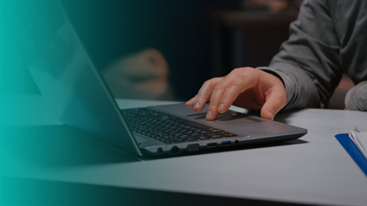 Conta: uma pessoa está mexendo no notebook com a mão direita. Ao lado, há outra pessoa sentada.