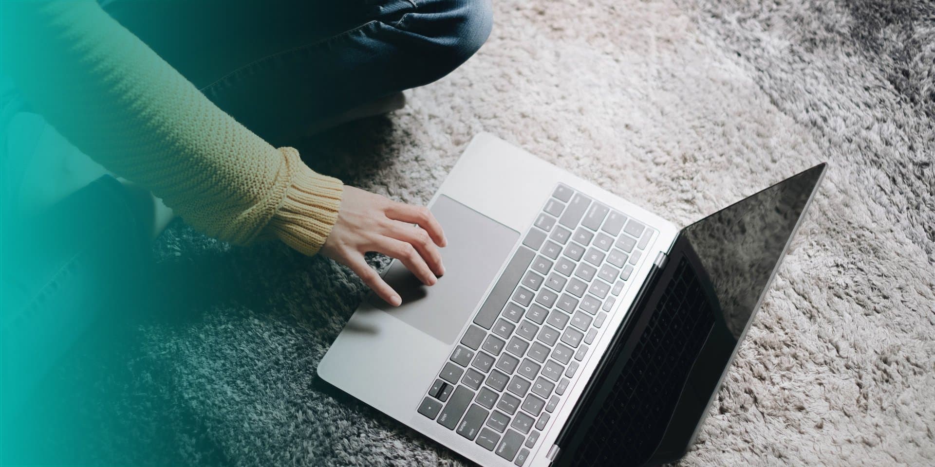Senha: uma pessoa está sentada no tapete, no chão, mexendo em um notebook.