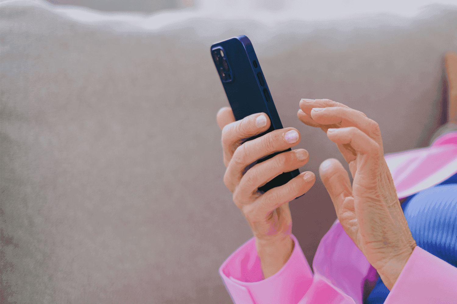 Pix Parcelado: uma mulher está sentada no sofá e mexendo no celular.