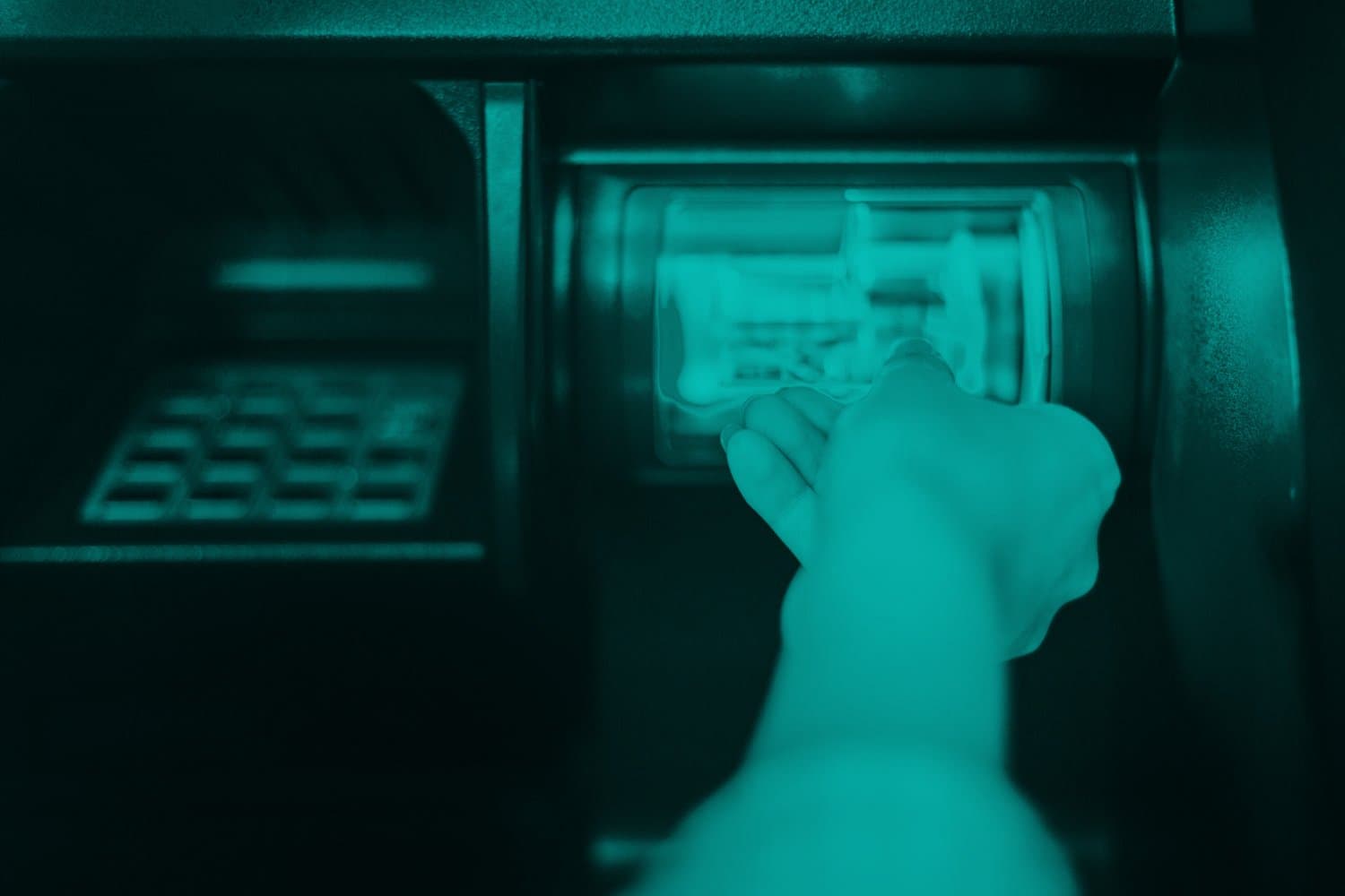Uma pessoa está inserindo o cartão num caixa eletrônico para sacar dinheiro.