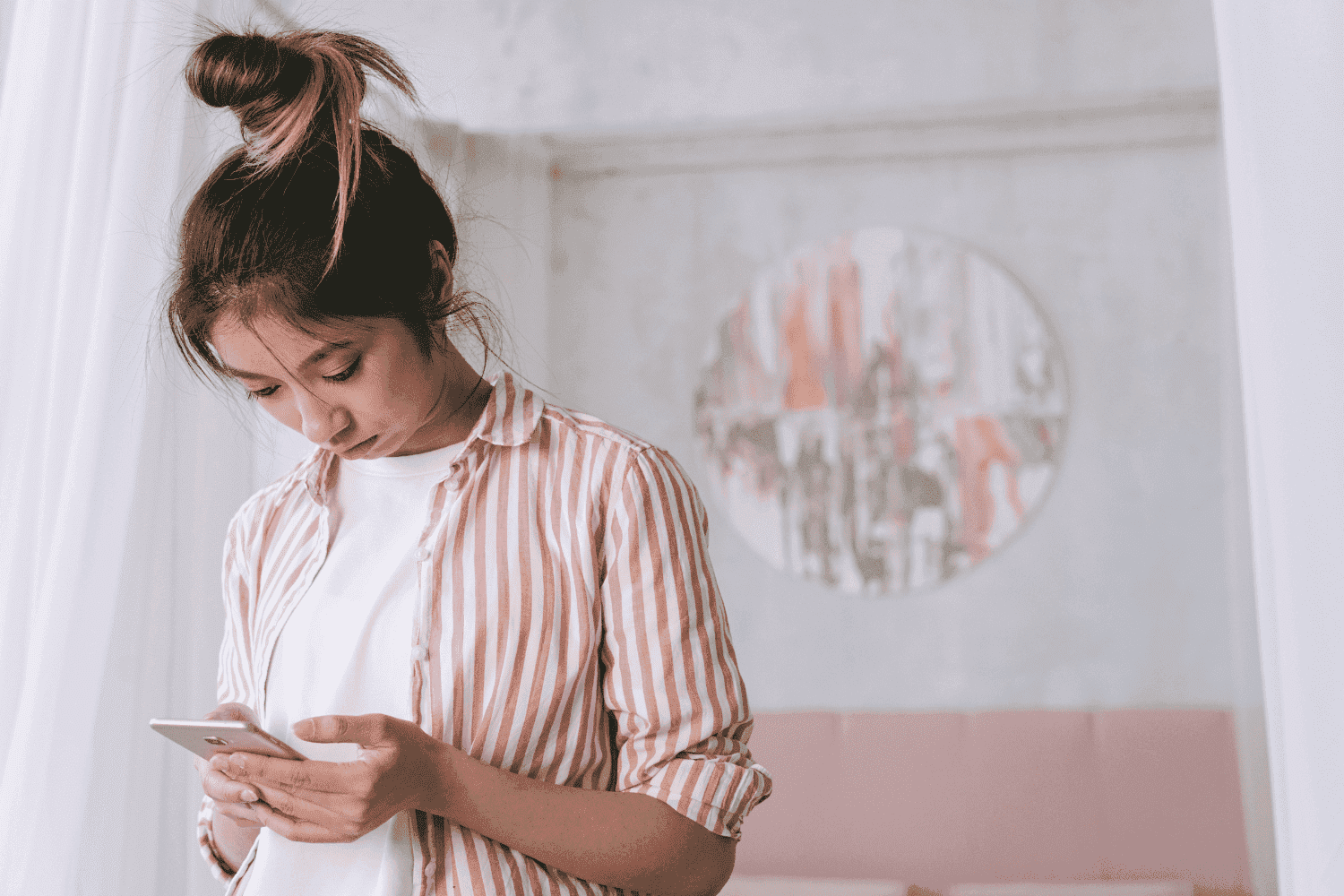 Extrato: uma mulher oriental está em pé, mexendo no celular.