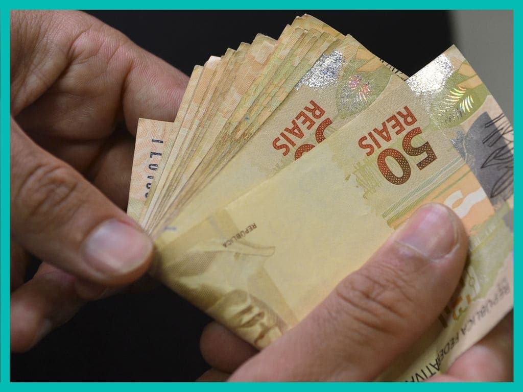 Auxílio Brasil: uma pessoa está contando algumas notas de cinquenta reais.