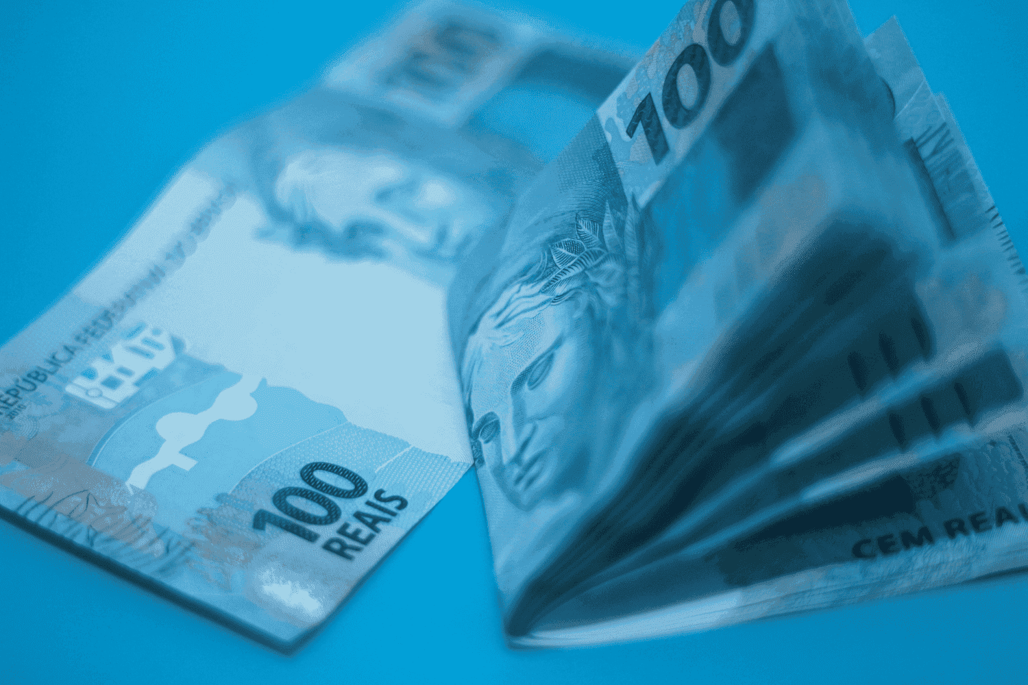 BPC: uma nota de cem reais está aberta, enquanto outras estão dobradas ao meio, juntas.