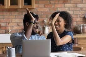 Capital inicial de uma empresa: homem e mulher em frente ao computador comemorando
