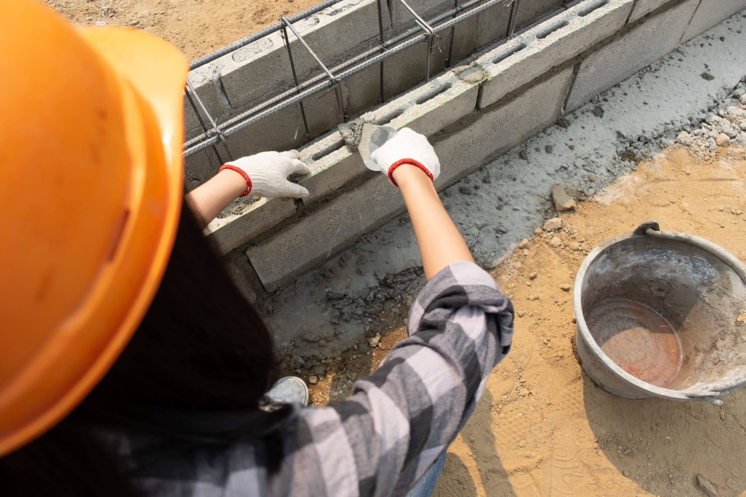 mulher construindo muro (usar o FGTS para comprar um terreno)