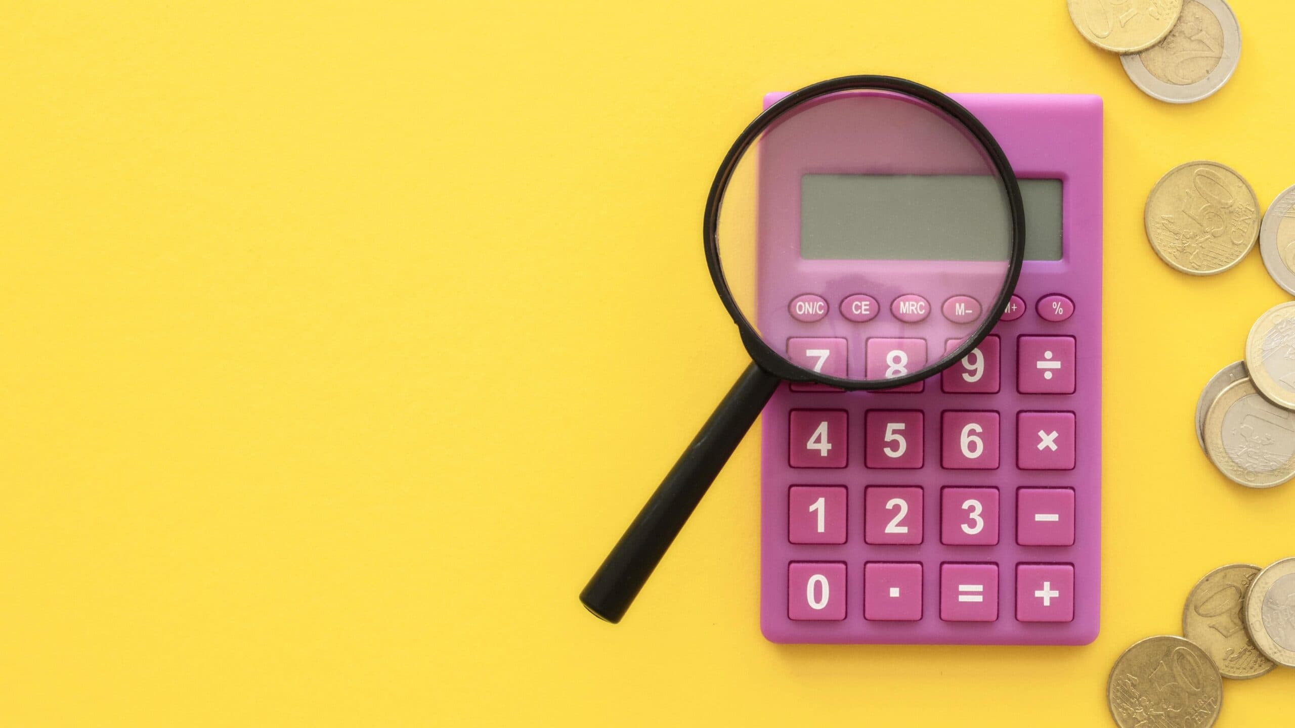 IPTU: uma lupa está apontada para uma calculadora e, ao lado, há algumas moedas espalhadas.