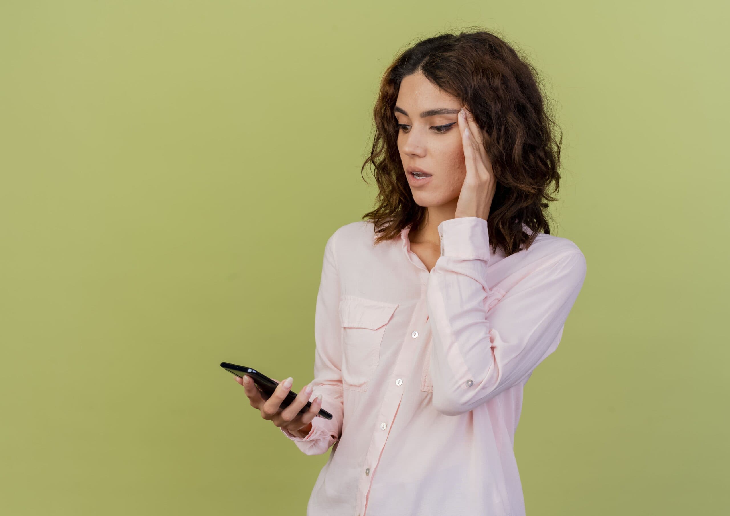 mulher preocupada segurando celular (golpes de empréstimos pelo WhatsApp)