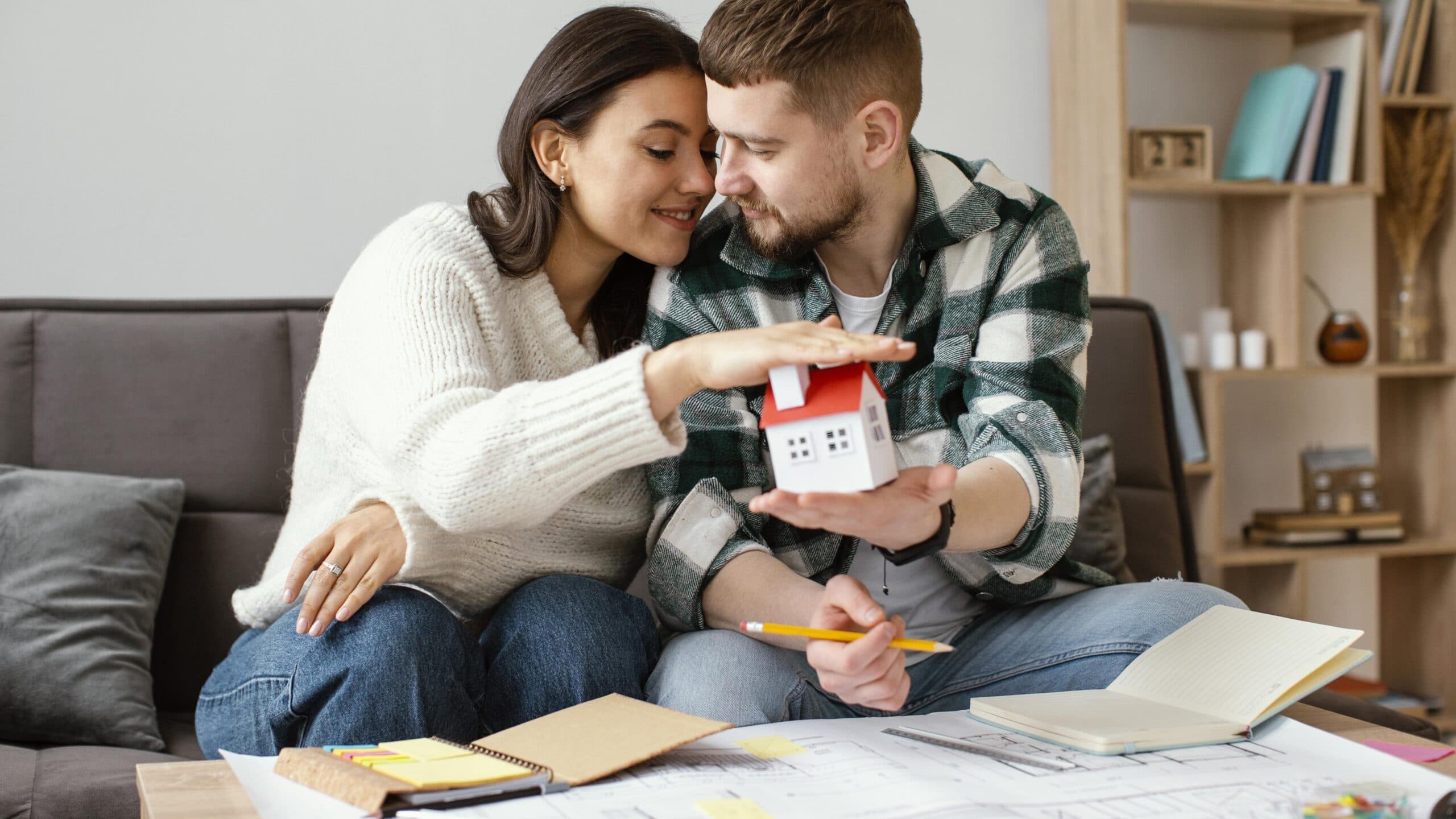 casal segurando casa de brinquedo (autofinanciamento)