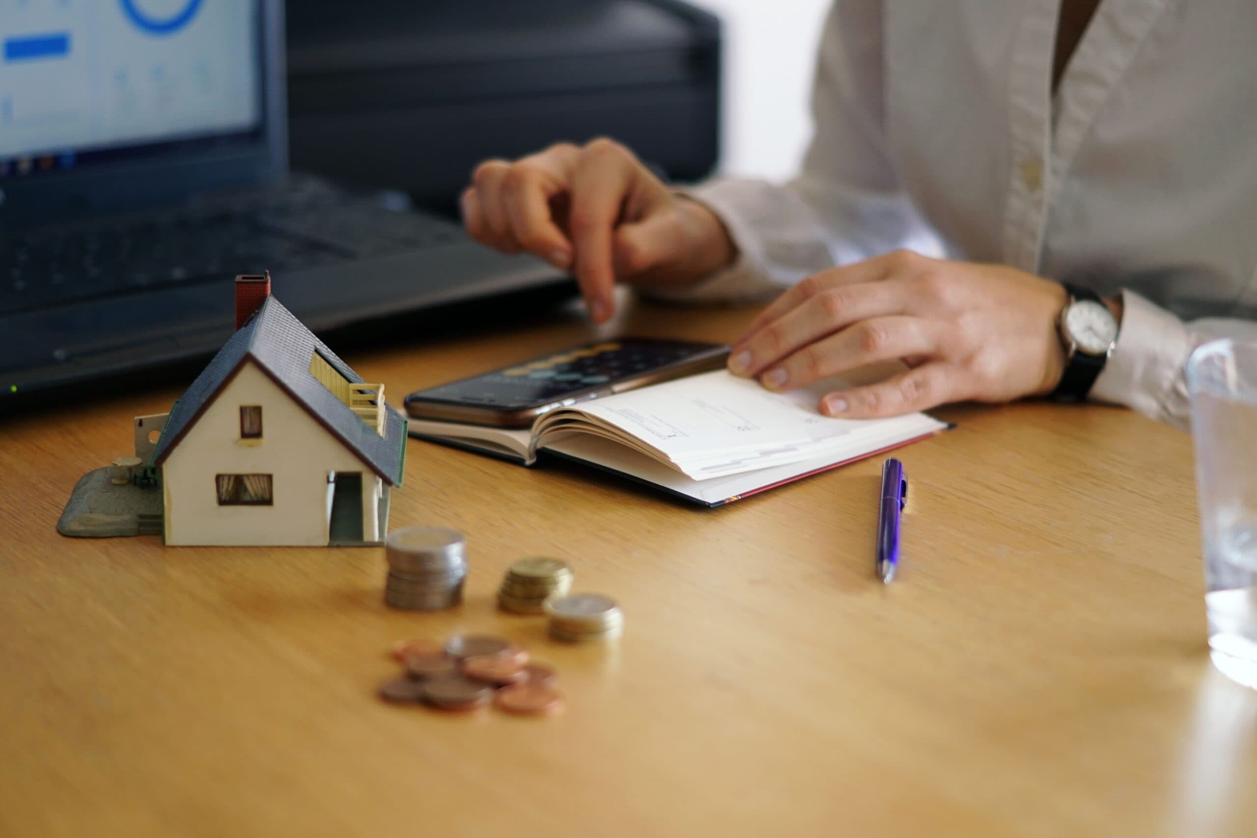 casa em miniatura, moedas e calculadora (consórcio para quitar financiamento)