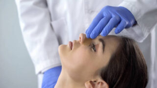 Consórcio para rinoplastia: um médico realiza o curativo no nariz de uma paciente.
