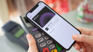 Uma pessoa aproxima o celular da maquininha e efetua o pagamento com a carteira da Apple.