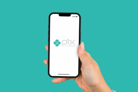 Empréstimo via Pix: uma pessoa branca segura um celular e, na tela, é mostrado o logo Pix. O fundo é verde.