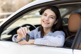 Mulher feliz dentro de veículo (seguro de auto para mulher)